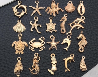 May include: A collection of gold-colored sea-themed charms, including dolphins, starfish, an octopus, seashells, a seahorse, a turtle, a crab, and a mermaid. These charms are designed with a loop at the top for easy attachment to jewelry or other crafts.
