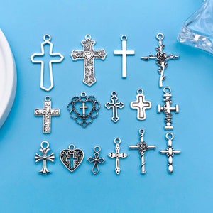 May include: A collection of 15 silver-toned metal cross charms with various designs, including simple crosses, ornate crosses, and crosses with hearts and flowers. These charms are perfect for jewellery making, scrapbooking, and other craft projects.