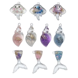 Può includere: Assortimento di 10 ciondoli in resina con conchiglie, sirene e meduse. I ciondoli sono trasparenti e riempiti di glitter colorati e conchiglie. Sono perfetti per aggiungere un tocco di fantasia a gioielli, portachiavi o altri lavoretti.
