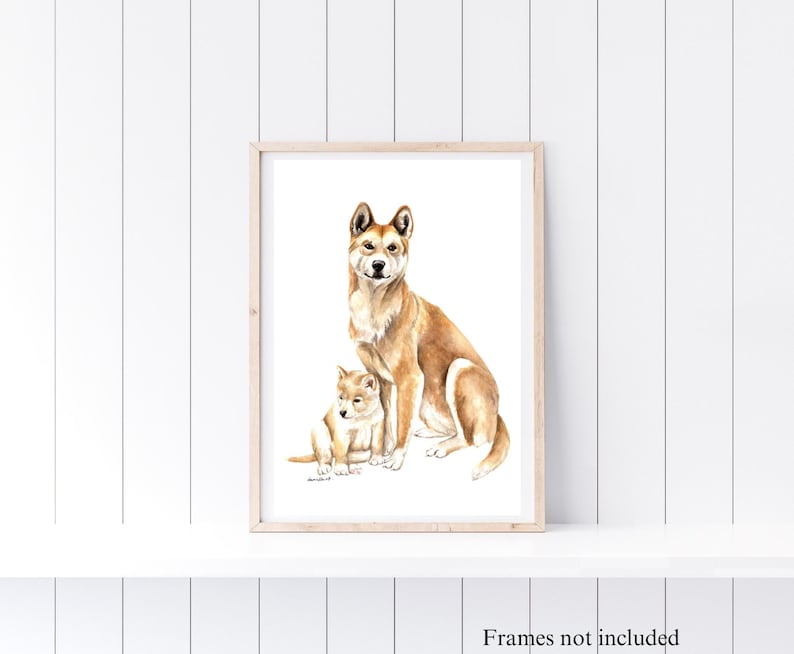 May include: Watercolor print of a tan-colored dog and puppy, set against a white background. The artwork is framed in a light wood frame. The print depicts the adult dog sitting and the puppy lying down.
