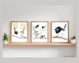 May include: Three framed watercolor paintings of blue and black birds with white bellies perched on branches. The birds are surrounded by yellow flowers and green leaves. The frames are made of wood and have a natural finish.