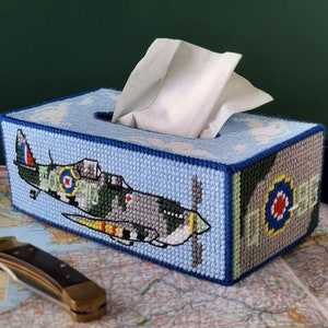 May include: A blue and green tissue box cover with a white tissue box inside. The cover features a colorful image of a vintage airplane with a red, white, and blue roundel.