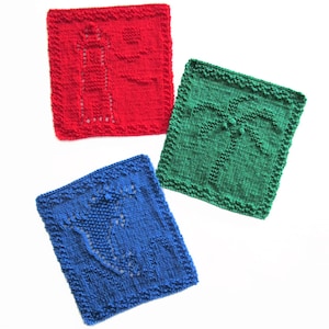 Op de afbeelding: Drie gebreide vierkanten in rood, groen en blauw. Het rode vierkant heeft een vuurtorenontwerp, het groene vierkant heeft een palmboom en het blauwe vierkant toont een gestileerd ontwerp. Elk vierkant heeft een getextureerde rand.