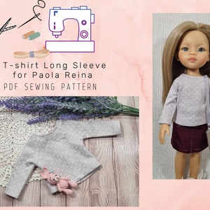 May include: A light gray long-sleeve t-shirt with white polka dots, designed for a Paola Reina doll. The image includes a doll wearing the shirt, a crochet bunny, and the text "T-shirt Long Sleeve for Paola Reina PDF SEWING PATTERN."