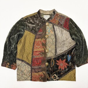 Puede incluir: Una chaqueta de manga larga con un diseño de patchwork de terciopelo verde oliva, tela dorada texturizada y paneles estampados en rojo, marrón y beige. La chaqueta tiene cuello mao, cuatro botones redondos y motivos florales bordados.