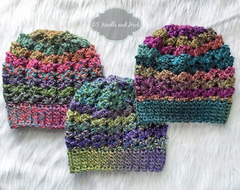 May include: Three colorful crocheted hats in shades of green, purple, teal, and pink. The hats are made with a textured stitch and have a ribbed brim.