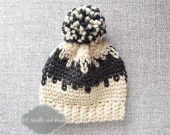 May include: A white and gray knitted beanie with a white pom pom on top. The beanie has a black and white chevron pattern on the top.