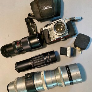 Può includere: Una macchina fotografica argentata con una custodia in pelle nera, un obiettivo nero e un obiettivo argentato con la scritta "Meyer Optik Gorlitz" su di essa.