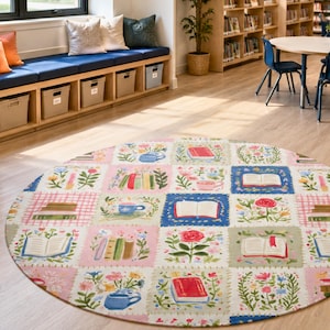 May include: A round area rug featuring a grid of square panels decorated with illustrations of open books, stacks of books, and colorful floral arrangements in shades of pink, blue, green, and red on a light-colored background.