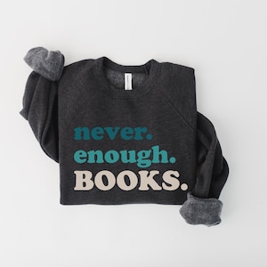 May include: A dark gray sweatshirt with the text "never. enough. BOOKS." printed in teal and beige.