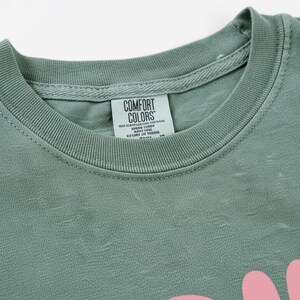 A green t-shirt with a label that reads "Comfort Colors" attached to the collar.
