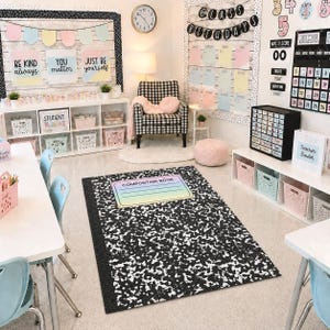 May include: A classroom interior featuring a composition book rug, white tables, and light blue chairs. The room is decorated with motivational posters, storage bins, and a black and white checkered armchair. A clock hangs on the wall.