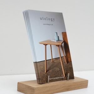 Puede incluir: Un tarjetero de madera con una pila de tarjetas. Las tarjetas muestran la palabra "utology" y una ilustraci&oacute;n de una peque&ntilde;a mesa. El tarjetero es de madera clara y tiene una base rectangular.