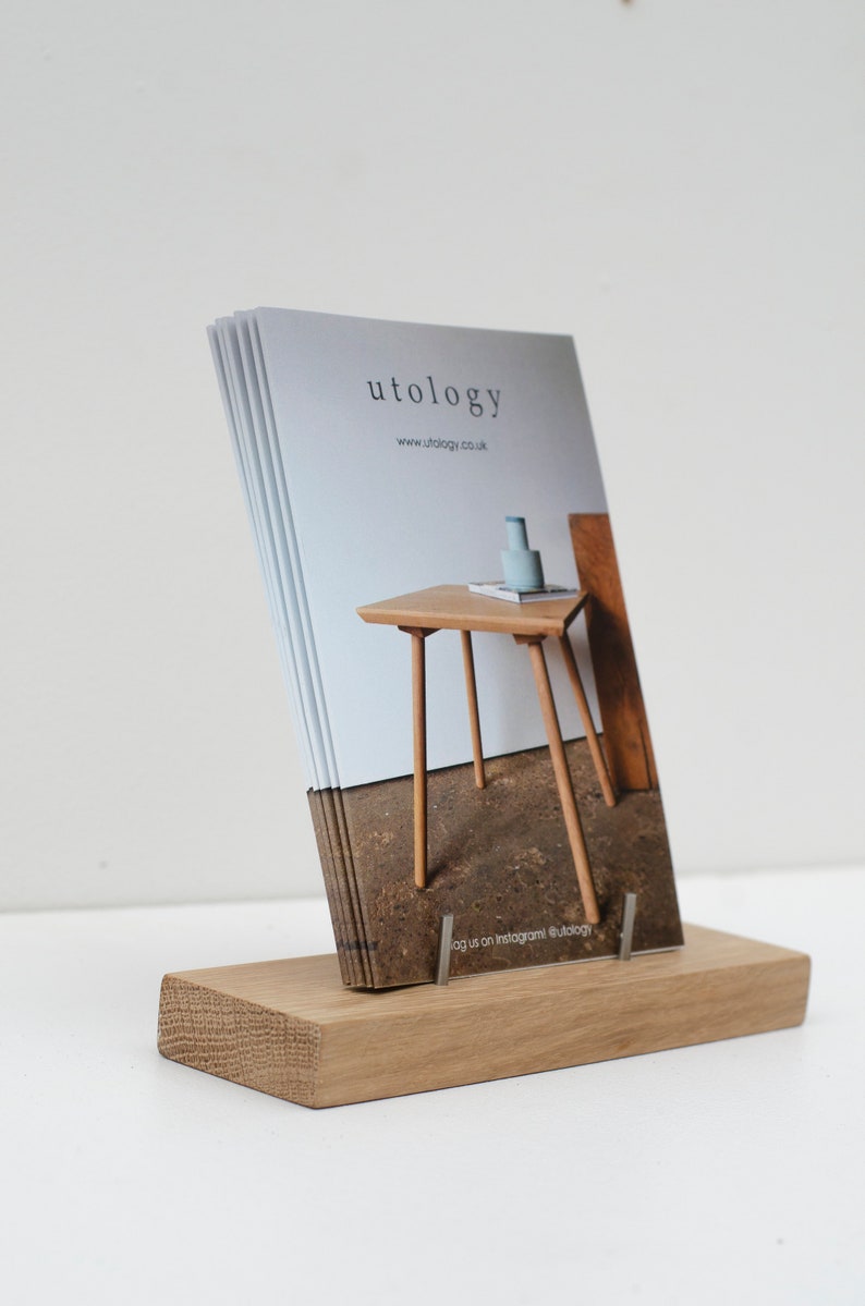Puede incluir: Un tarjetero de madera con una pila de tarjetas. Las tarjetas muestran la palabra "utology" y una ilustraci&oacute;n de una peque&ntilde;a mesa. El tarjetero es de madera clara y tiene una base rectangular.