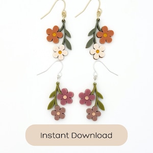 Puede incluir: Dos pares de pendientes colgantes con motivos florales. El par superior tiene flores color naranja óxido y crema sobre tallos verde oliva. El par inferior tiene flores malva y rosa empolvado sobre tallos verde oliva. Ganchos de metal dorado.