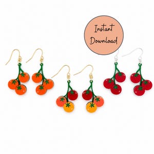 May include: Tomato-themed earrings with gold and silver hooks. The earrings feature a cluster of three tomatoes in shades of red, orange, and yellow, attached to a green stem. The earrings are designed with a playful and colorful aesthetic.