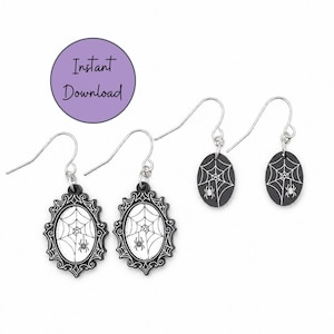 May include: Two pairs of dangle earrings with silver-toned hooks. One pair features oval black charms with white spiderweb and spider illustrations. The other pair has ornate black frames surrounding white centers with spiderweb and spider designs.