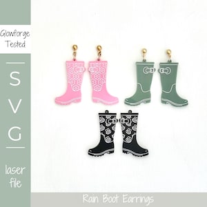 Puede incluir: Pendientes de botas de lluvia rosas, verdes y negras. Las botas rosas tienen un diseño floral, las verdes una hebilla y las negras un estampado de paraguas y nubes. Cortados con láser.