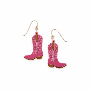 May include: A pair of drop earrings shaped like cowboy boots. The boots are pink with a white floral pattern and brown wood-tone accents at the top and heel. Each earring features a gold-toned metal hook for attachment to the earlobe.