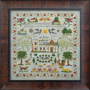 Può includere: Un sampler a punto croce incorniciato con un design dettagliato. Il sampler presenta un edificio centrale, alberi, animali e motivi floreali. Il testo include gli anni 1607 e 2025 e frasi latine. La cornice è in legno marrone scuro.
