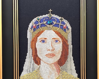 Pode incluir: Um retrato bordado em ponto de cruz emoldurado de uma mulher usando uma coroa e véu. A mulher tem cabelo ruivo e olhos azuis. A coroa é azul e dourada com joias vermelhas e verdes. O fundo é preto.