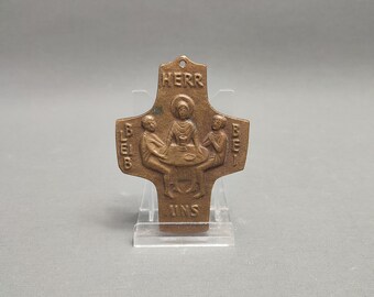 May include: A bronze cross with a depiction of Jesus and two disciples at the Last Supper. The words "Herr" and "uns" are inscribed on the cross.