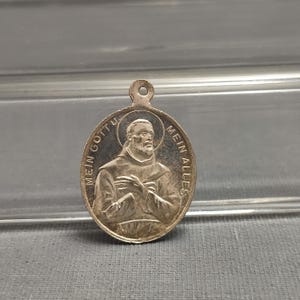 Puede incluir: Pendiente de plata con una imagen en relieve de un hombre con barba y el texto "Mein Gott Mein Alles" alrededor del borde.