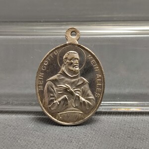 Puede incluir: Pendiente de plata con una imagen en relieve de un hombre con barba y el texto "Mein Gott Mein Alles".