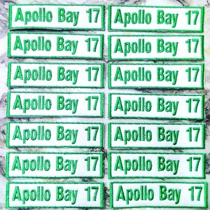 May include: Eight pairs of white iron-on patches with green borders. Each patch reads "Apollo Bay 17".