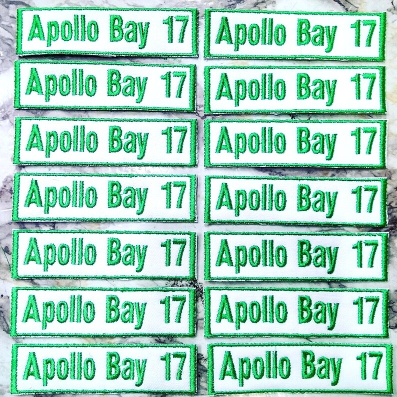 May include: Eight pairs of white iron-on patches with green borders. Each patch reads "Apollo Bay 17".