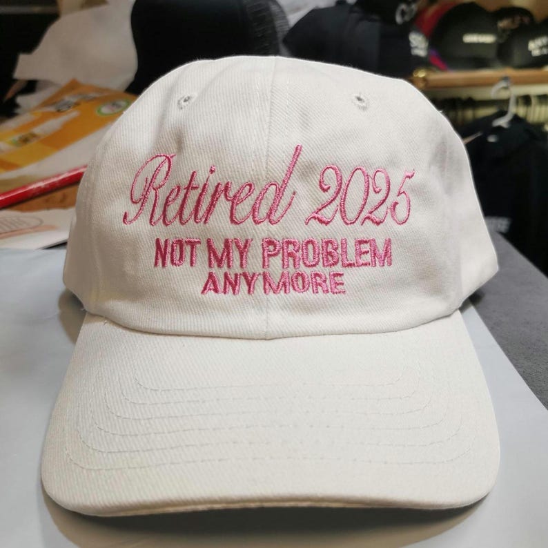 May include: White baseball cap with pink embroidery that reads "Retired 2025 Not My Problem Anymore".