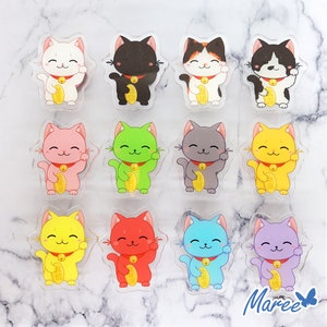 Può includere: Un set di 10 figurine di gatti portafortuna colorati. Ogni gatto è di un colore diverso, tra cui rosa, verde, giallo, rosso, blu e viola. I gatti sono tutti in posizione seduta con la zampa destra alzata, un simbolo tradizionale di buona fortuna.