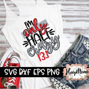 Puede incluir: Camiseta blanca de tirantes con el texto "I'm only half crazy 13.1" en letras rojas y grises. El texto está sobre un fondo gris. La camiseta está sobre una superficie blanca con un par de pantalones vaqueros azules y un par de zapatillas blancas.