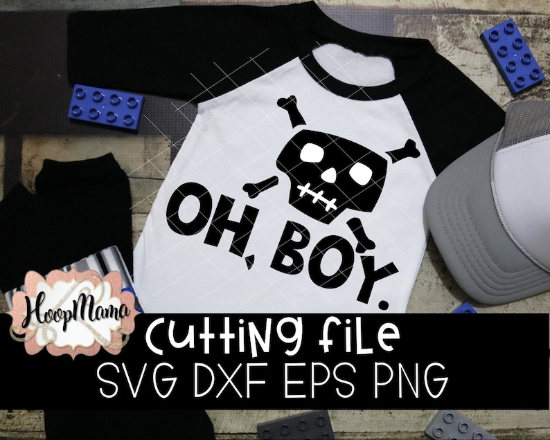 May include: A white onesie with black text that reads "Oh Boy!" and a black and white skull and crossbones design. The onesie is on a wooden surface with blue and gray toy blocks.