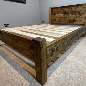 May include: A rustic wooden bed frame with a dark brown stain. The bed frame has a headboard and a slatted base.