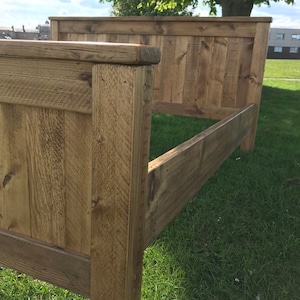 Puede incluir: Un marco de cama de madera con un cabecero hecho de tablones de madera recuperados. El marco est&aacute; te&ntilde;ido de un color marr&oacute;n claro y tiene un aspecto r&uacute;stico.