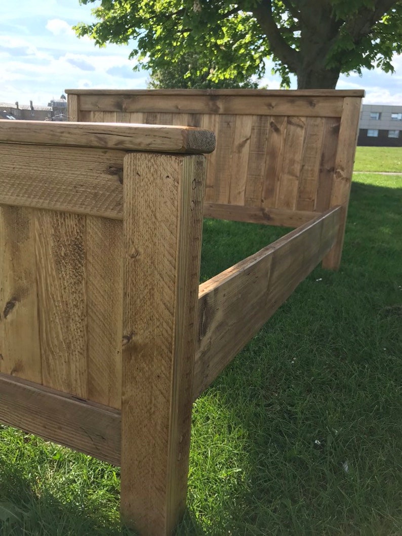 Puede incluir: Un marco de cama de madera con un cabecero hecho de tablones de madera recuperados. El marco est&aacute; te&ntilde;ido de un color marr&oacute;n claro y tiene un aspecto r&uacute;stico.