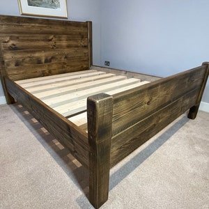 May include: A dark brown wooden bed frame with a high headboard and a slatted base.
