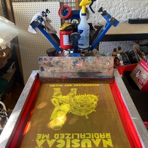 Puede incluir: Un marco de serigraf&iacute;a amarillo con un dise&ntilde;o de una persona sosteniendo una esfera grande con el texto "MUSIC.A RADICALIZED ME. ACCOMPLICES NOT ALLIES." impreso en &eacute;l.