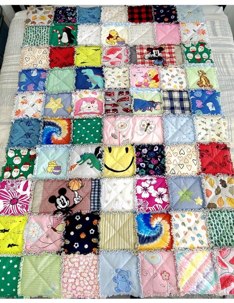 K&ouml;nnte beinhalten: Eine bunte Patchwork-Decke aus Stoffquadraten mit verschiedenen Comicfiguren, Tieren und Mustern. Die Decke ist in verschiedenen Farben gehalten, darunter Rot, Blau, Gr&uuml;n, Gelb und Pink.