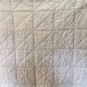 K&ouml;nnte beinhalten: Eine wei&szlig;e und graue gestreifte Steppdecke mit einem Rautenmuster. Die Steppdecke ist mit einem einfachen Stich gesteppt.