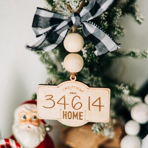 May include: A wooden Christmas ornament with a black and white checkered ribbon, wooden beads, and the text "Christmas -2021- 34614 HOME".