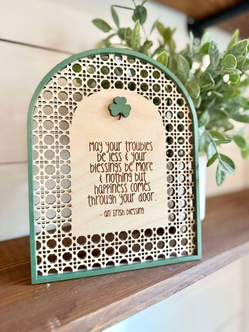 Irish Blessing Sign by Walnut + Birch. Irish Blessing reads "May your troubles be less & and your blessings be more & nothing but happiness comes through your door". Rattan oval shaped sign with green frame and 3 leaf clover.