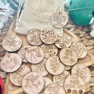May include: A set of 20 wooden Christmas activity tokens in a white drawstring bag. The tokens feature various Christmas activities such as listening to holiday music, decorating the tree, baking cookies, and wrapping gifts. The tokens are perfect for a Christmas advent calendar or a fun family activity.