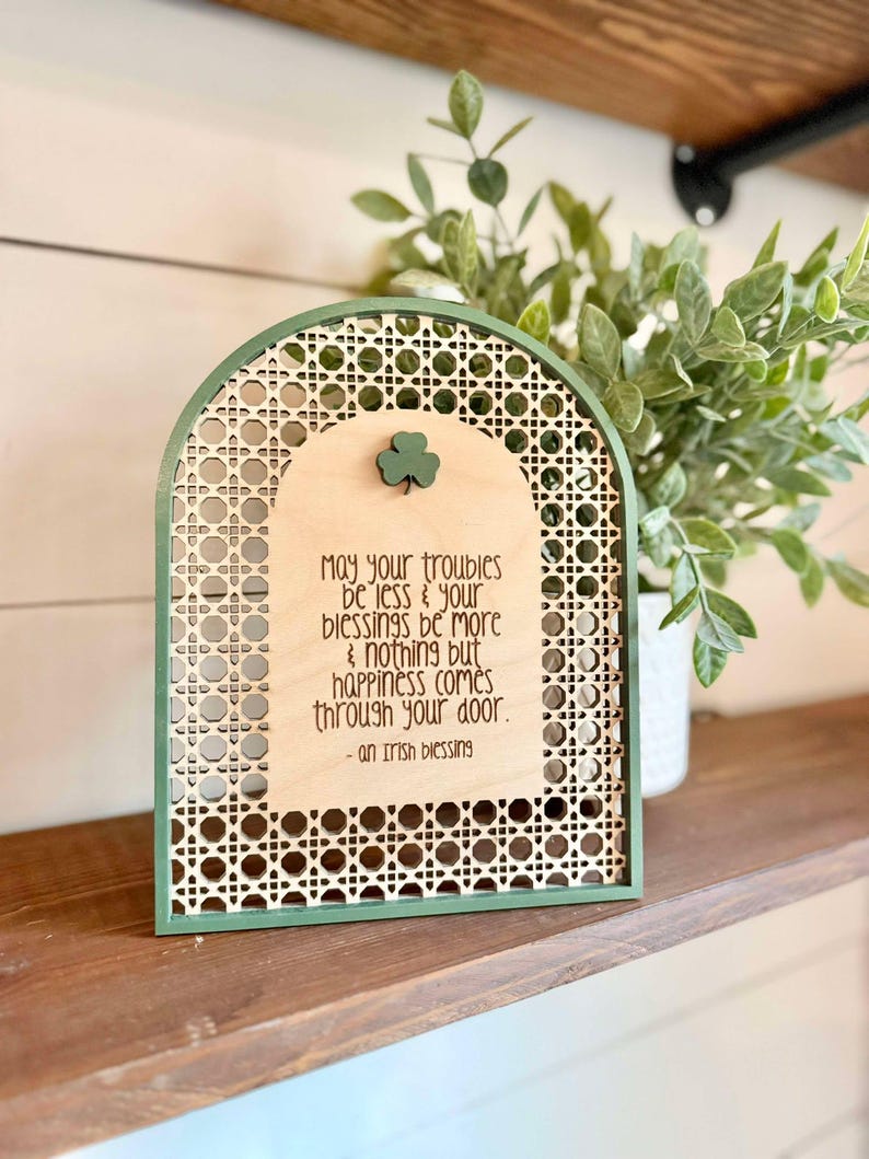 Irish Blessing Sign by Walnut + Birch. Irish Blessing reads "May your troubles be less & and your blessings be more & nothing but happiness comes through your door". Rattan oval shaped sign with green frame and 3 leaf clover.