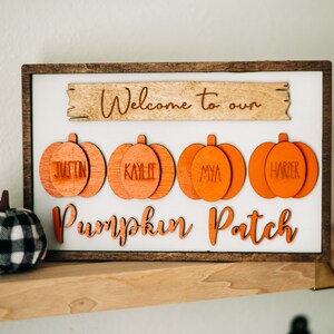 May include: Wooden sign with the text "Welcome to our Pumpkin Patch" and four orange pumpkin-shaped ornaments with the names Justin, Kaylee, Mya, and Harper.
