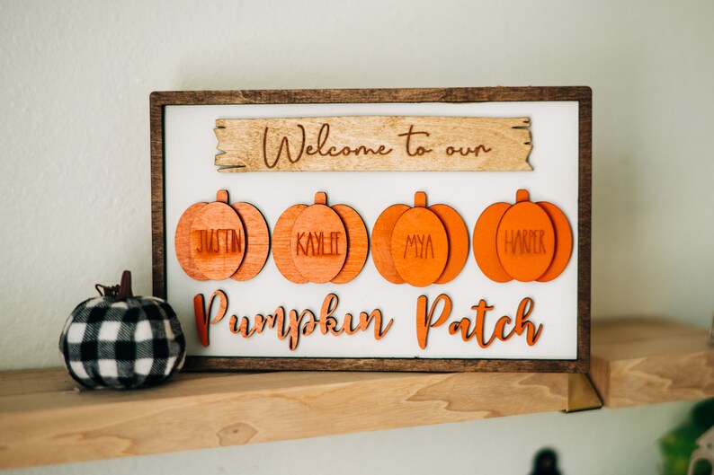May include: Wooden sign with the text "Welcome to our Pumpkin Patch" and four orange pumpkin-shaped ornaments with the names Justin, Kaylee, Mya, and Harper.