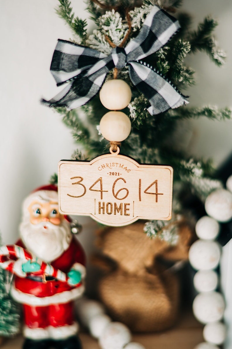 May include: A wooden Christmas ornament with a black and white checkered ribbon, wooden beads, and the text "Christmas -2021- 34614 HOME".