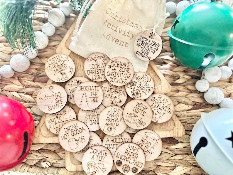 May include: A set of 16 wooden Christmas activity tokens with various holiday-themed illustrations and text. The tokens are in a small burlap bag with the words "Christmas Activity Advent" printed on it.  The tokens include activities such as "Listen to Holiday Music", "Go See Santa", "Write a Letter to Santa", "Drink Hot Cocoa", "Decorate the Tree", "Bake Some Christmas Cookies", "Make Gingerbread House", "Take Family Photo", "Wrap Gifts", "Send Christmas Cards", "Play a Game with Family", "Read a Holiday Book", "Make Paper Snowflakes", "Donate a Toy", "Eat Candy Cane", "A Holiday Craft", and "Look at Christmas Lights".