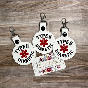 May include: Three white keychains with black text and a red medical symbol. Each keychain says "Type II Diabetic".